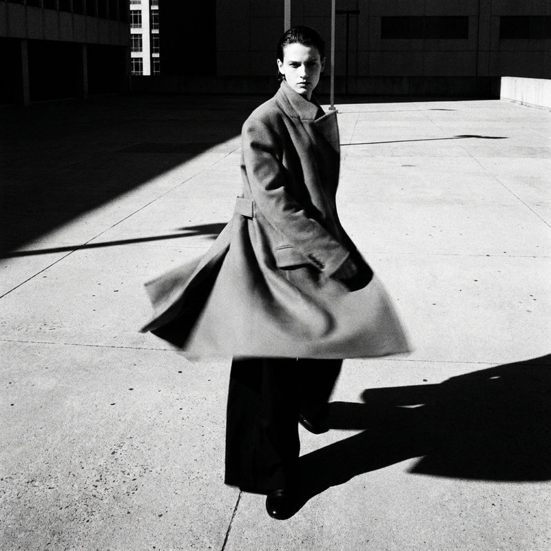 Editorial fashion, model in structured coat, urban plaza