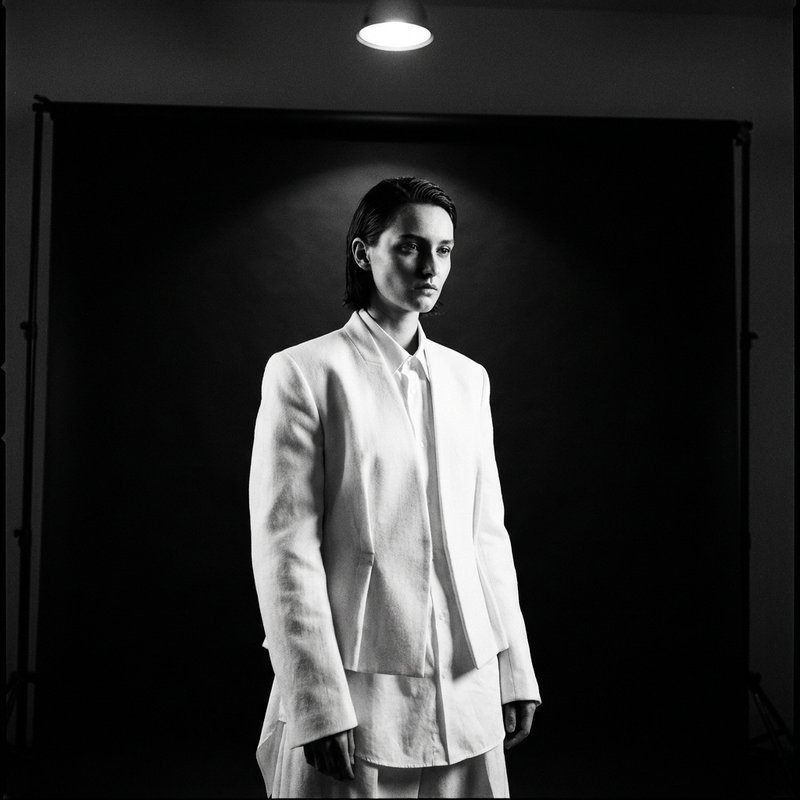 Studio portrait, dramatic overhead light against black